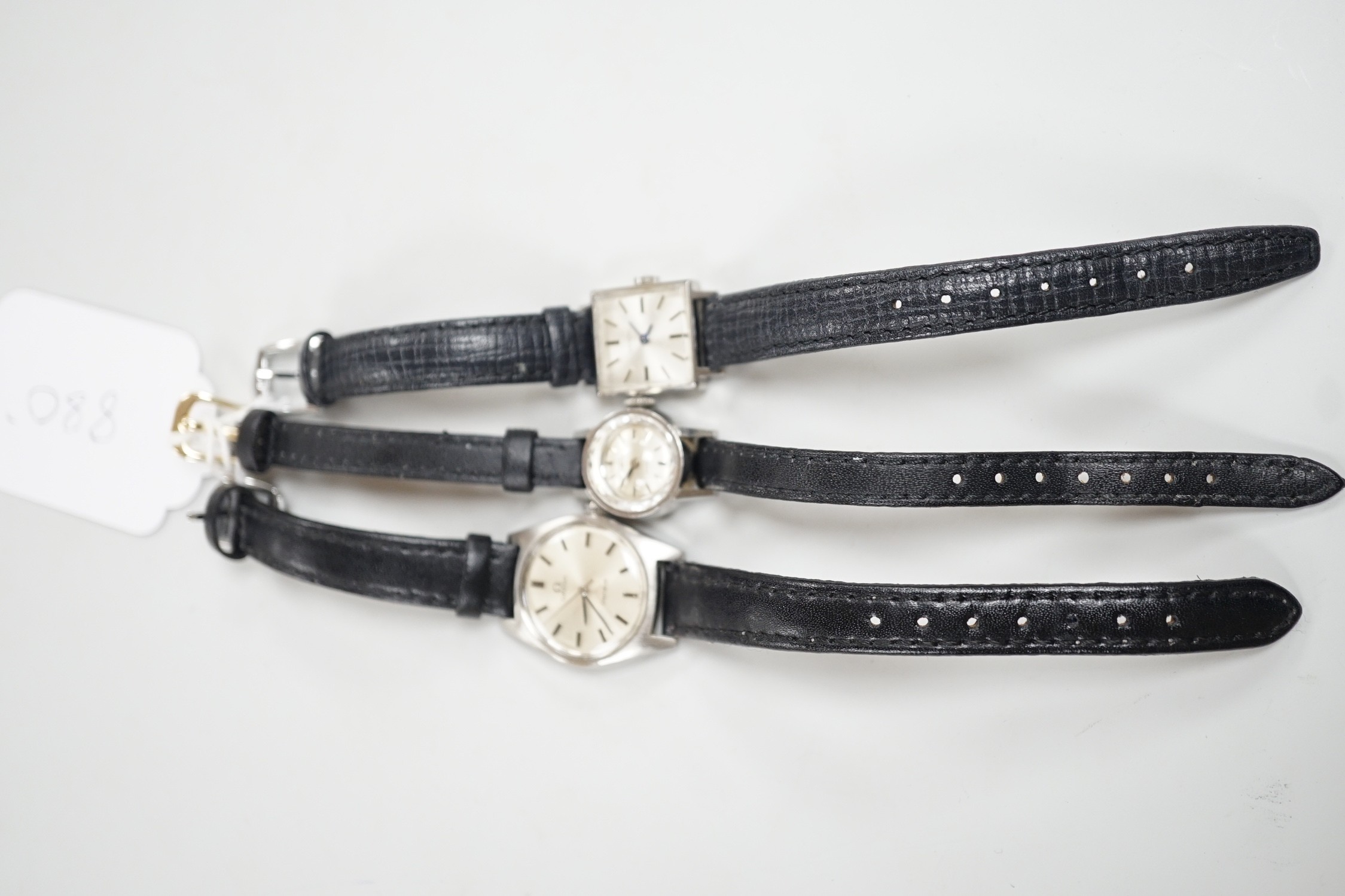 A lady's stainless steel Omega manual wind wrist watch, with baton numerals, together with a lady's stainless steel Zenith square dial manual wind wrist watch and a similar Girard Perregaux manual wind wrist watch.